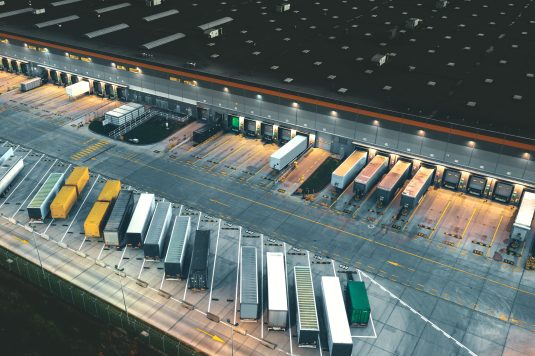 Top view of many trailers and containers near the logistics warehouse, in the evening